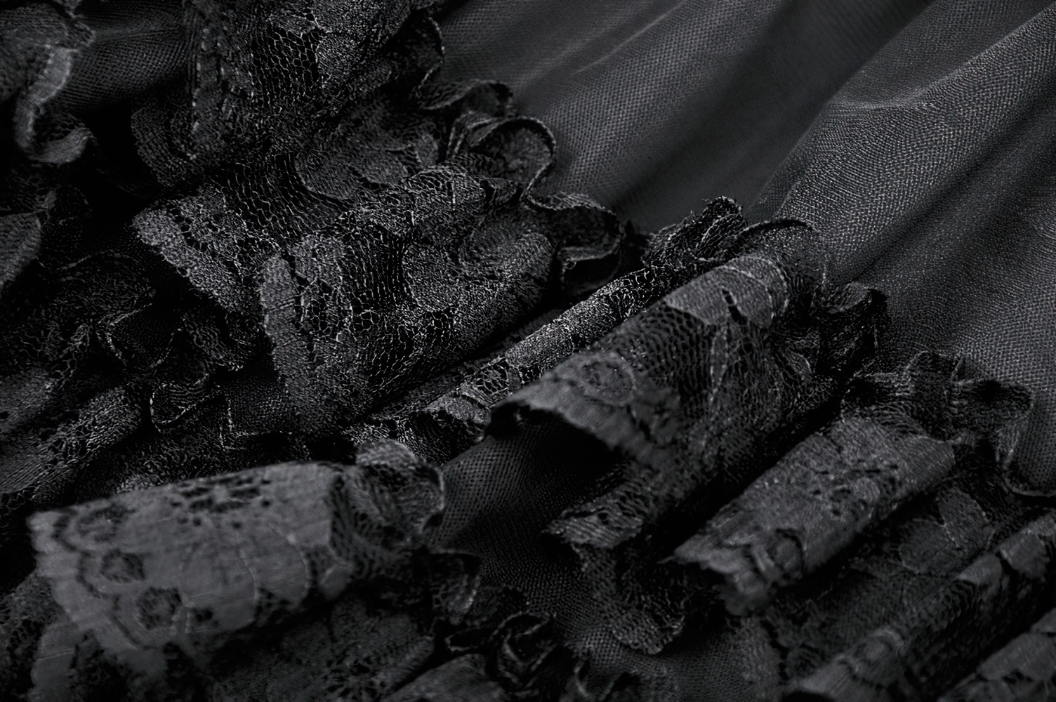 Close-up of dark lace trim on a black fabric, highlighting the delicate details of gothic style.