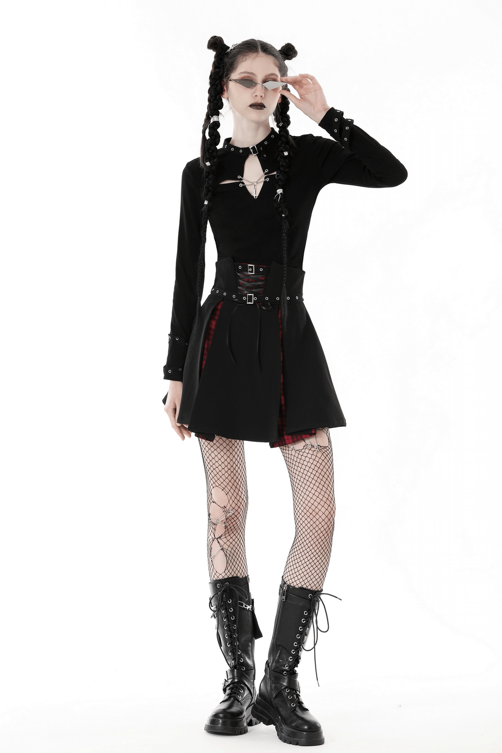 Gothic punk woman wearing a black crop top with cutout cross, fishnet tights, and combat boots, exuding edgy style.