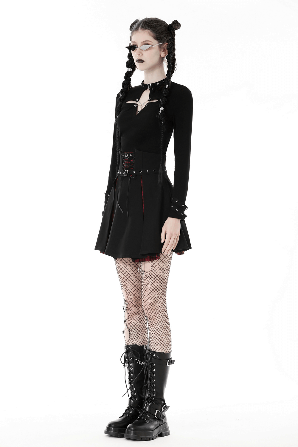 Dark gothic punk outfit featuring a black cutout crop top, fishnet tights, and combat boots, perfect for edgy street style.
