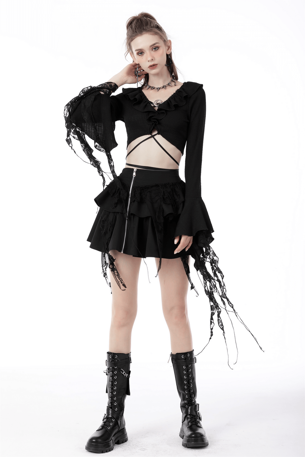 Model wearing a dark gothic crop top with ruffle neck and ripped sleeves styled with a flared skirt and combat boots.