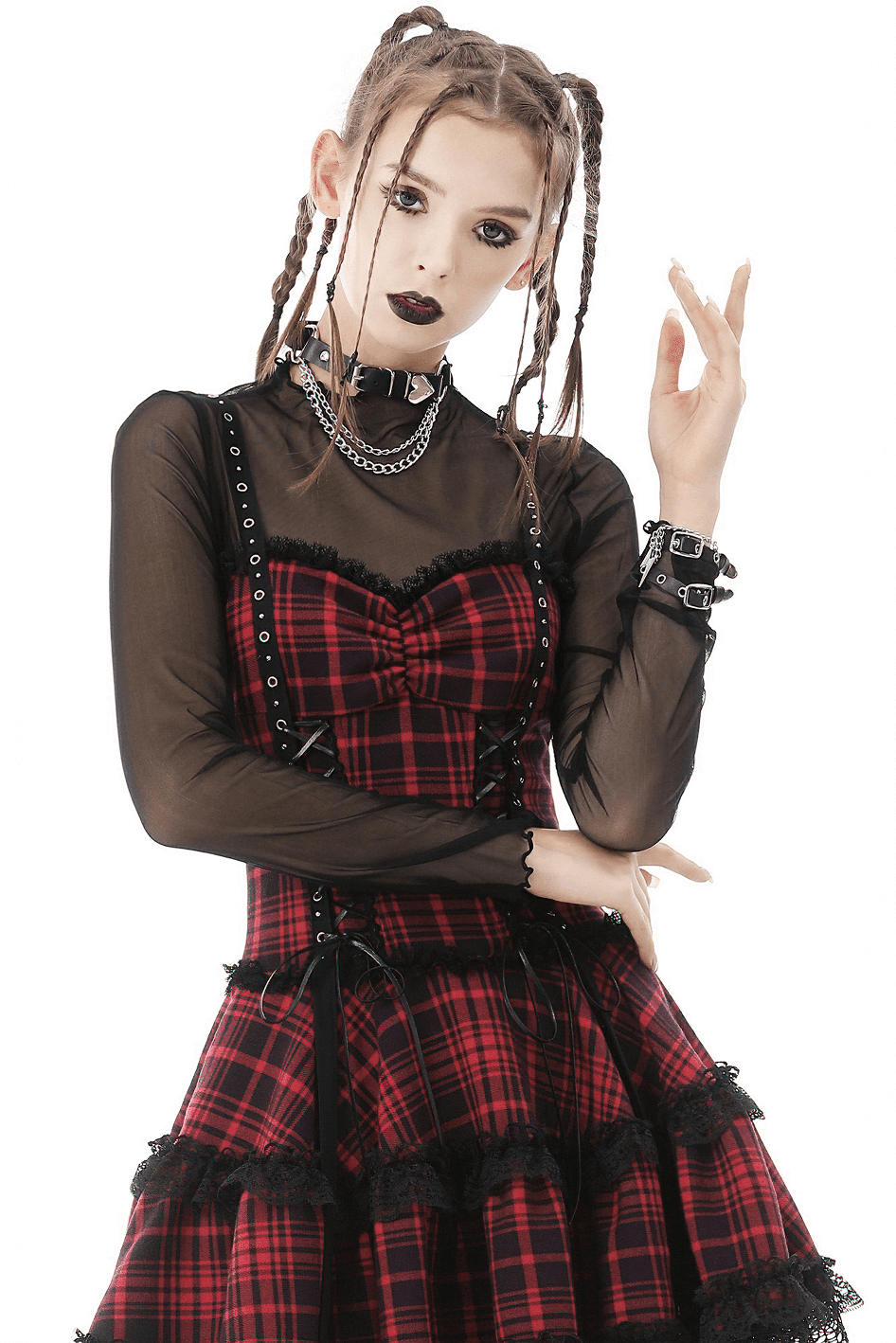 Gothic model in sheer black long-sleeve top with plaid dress and edgy accessories, showcasing a daring punk style.