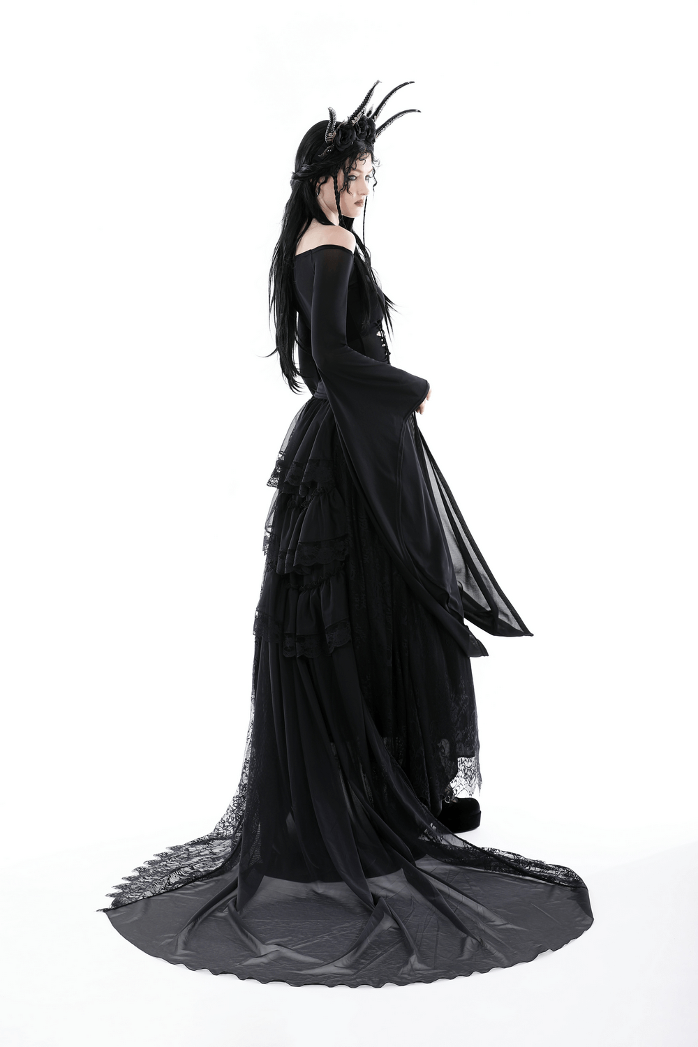Elegant woman in flowing black dress with dramatic sleeves, showcasing gothic style and intrigue.