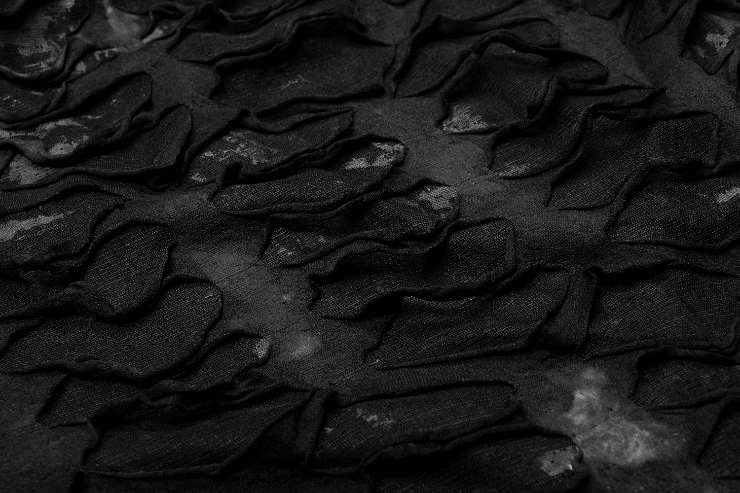 Close-up of textured black fabric with layered ripples, showcasing unique gothic design elements.