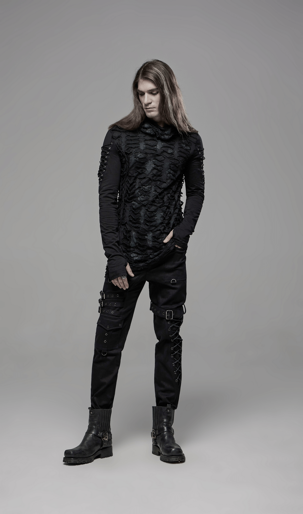 Male model wearing a dark, ripped Gothic hoodie with lace-up sleeves and edgy pants, showcasing a punk fashion vibe.