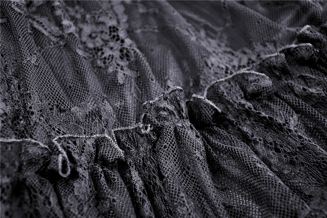 Close-up of dark lace fabric showcasing intricate details of a gothic off-the-shoulder dress.