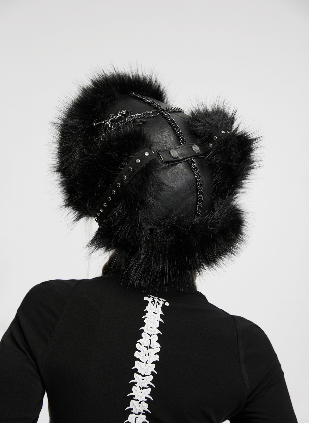 Back view of a dark plush punk hat with ear protection and metal accents, featuring tattered mesh and faux fur.