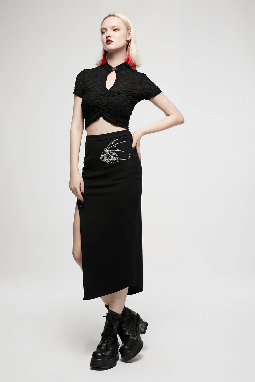 Model showcasing a dark punk asymmetric pencil skirt with dragon embroidery, styled with a cropped top and chunky boots.