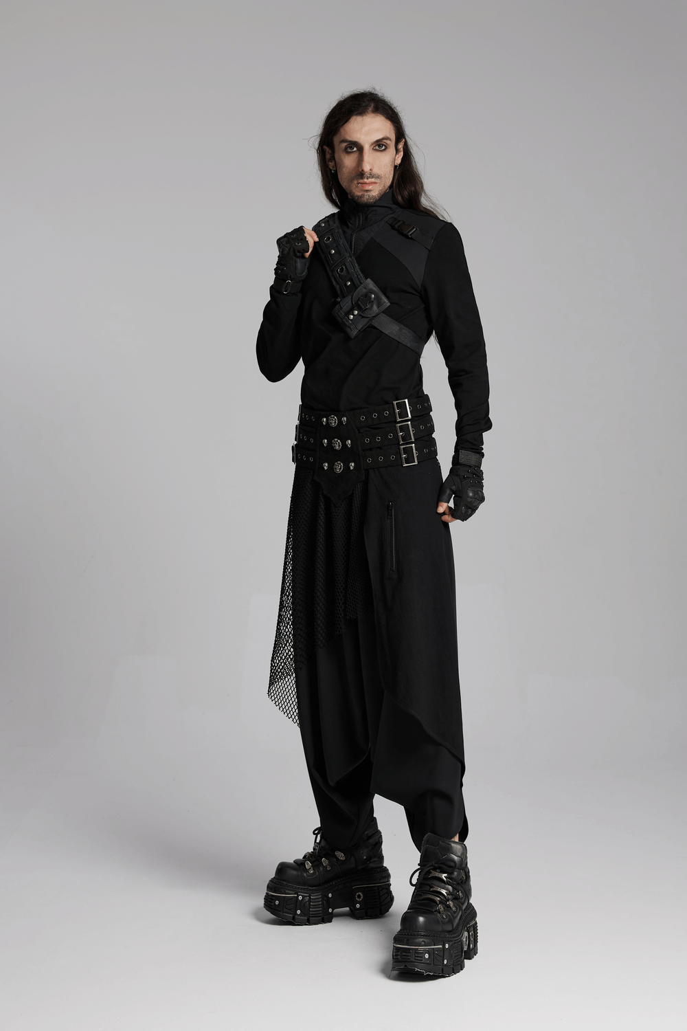 Dark punk model showcasing loose fit harem pants with mesh layers and edgy accessories in a high-fashion pose.