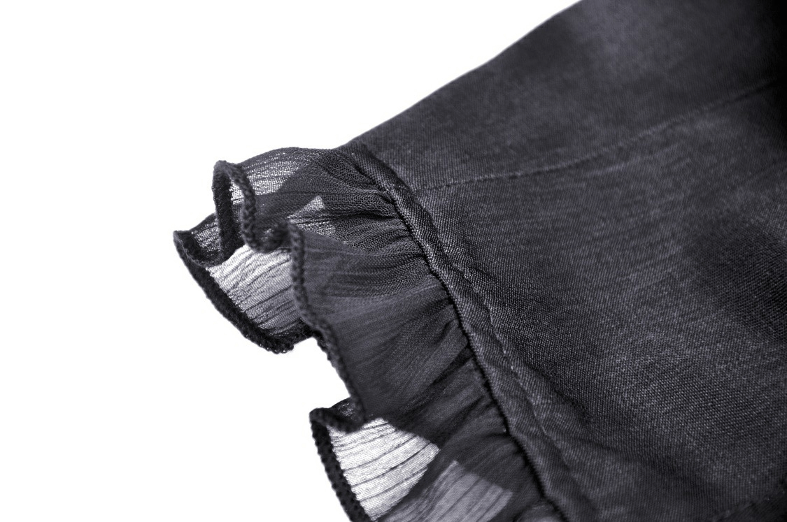 Close-up of ruffled black fabric detail on a dark punk zip crop top, showcasing its gothic style and elegant lace texture.