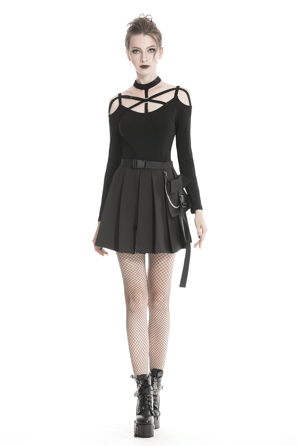 Edgy model in black pleated mini skirt with chain, fishnet stockings, and stylish goth-inspired top.