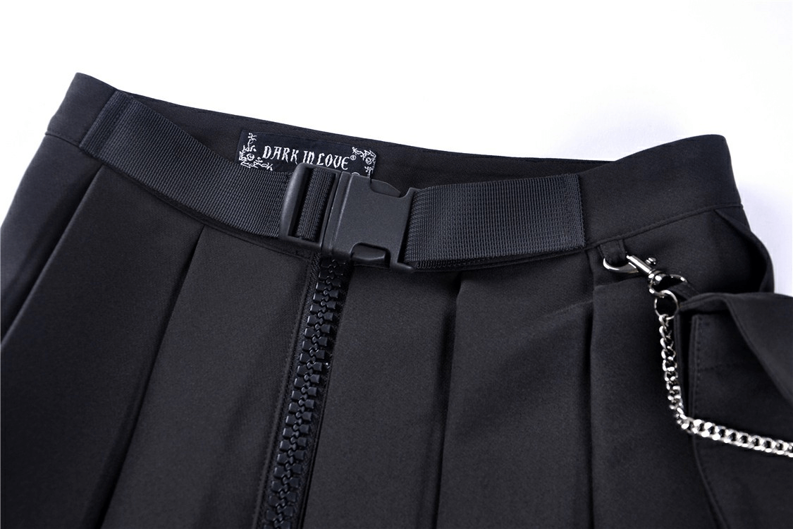 Close-up of a black pleated mini skirt with chain detail and zipper, showcasing edgy punk style.