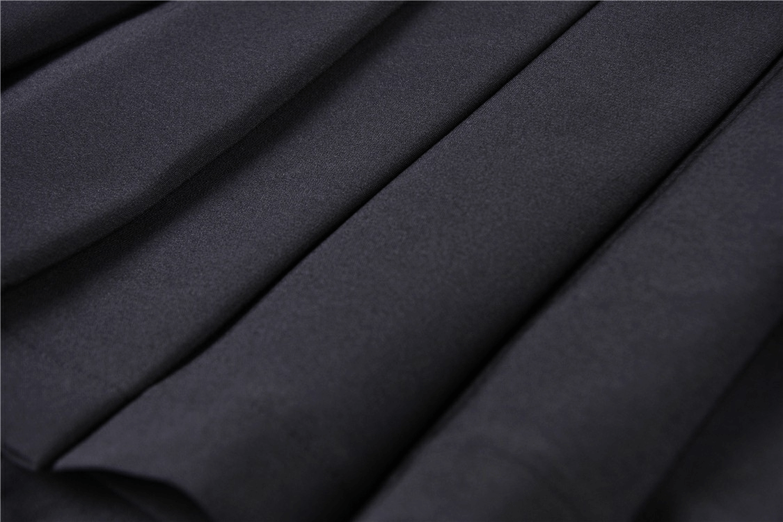 Close-up of dark punk pleated mini skirt showcasing sleek fabric and deep pleats for edgy fashion.