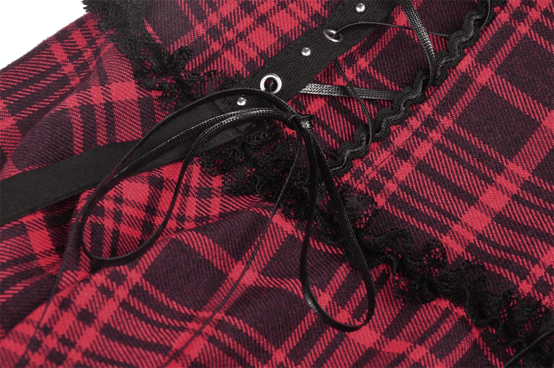 Close-up of red and black plaid fabric with metal cross-tie trim and lace accents on a mini dress.