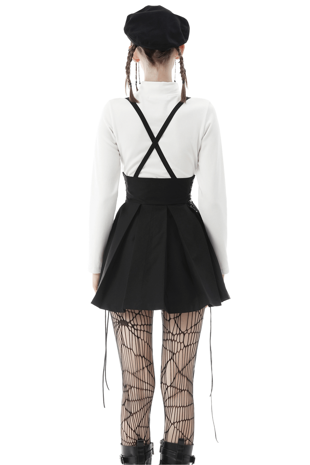 Gothic dark punk suspender skirt with buckle detailing worn with fishnet stockings and a stylish hat.