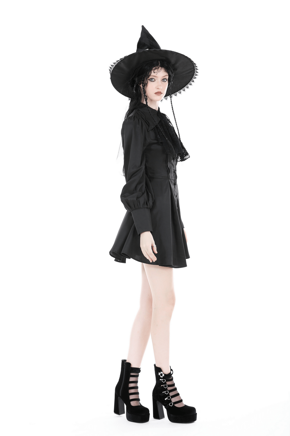 Model wearing a black ruffled neckline long-sleeved dress with a witch hat and chunky platform shoes.