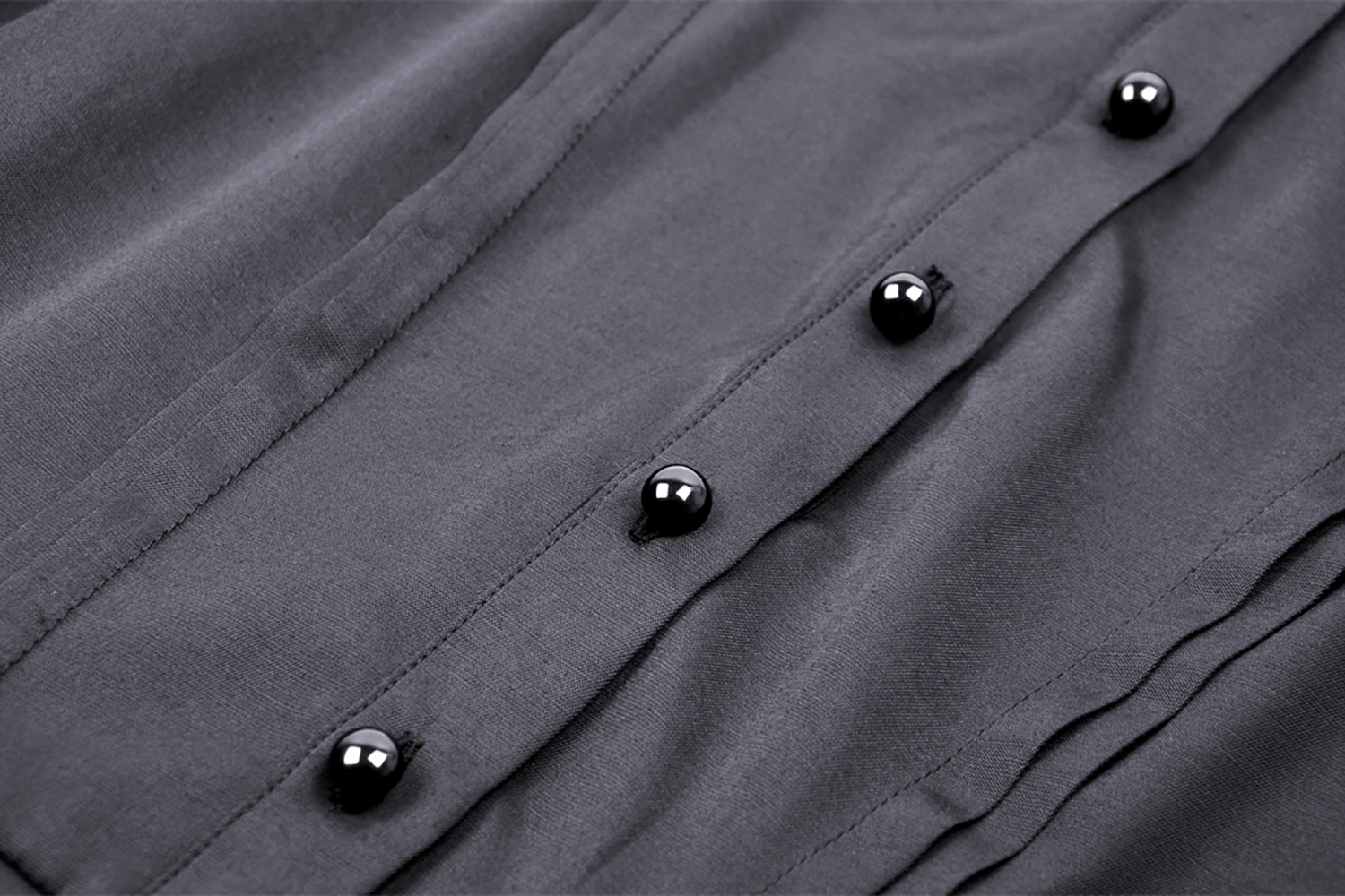 Close-up of black button details on a dark, ruffled dress, showcasing gothic fashion elements.