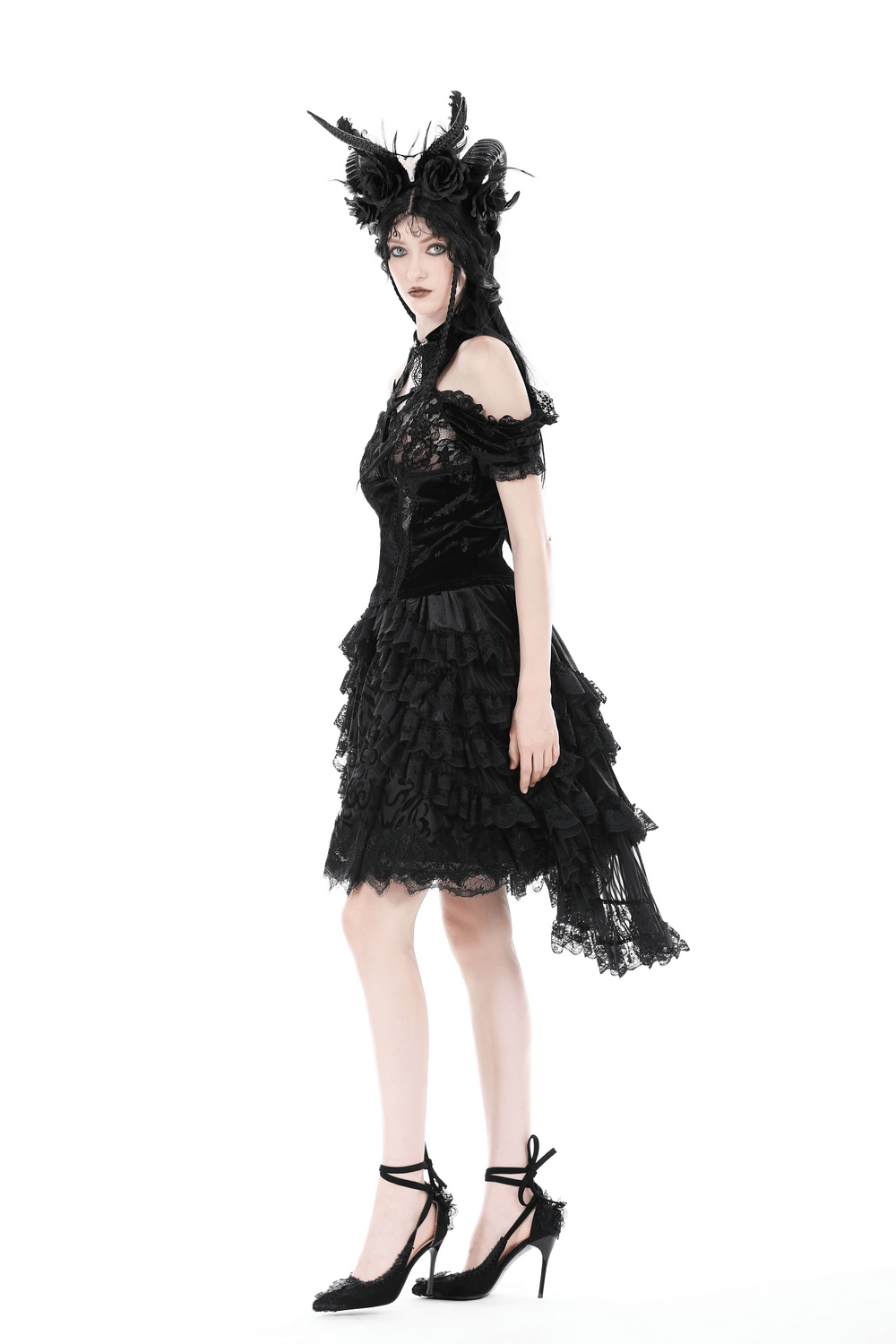Dark romantic goth woman in a black lace high-low skirt with ruffles, showcasing a whimsical gothic fashion style.