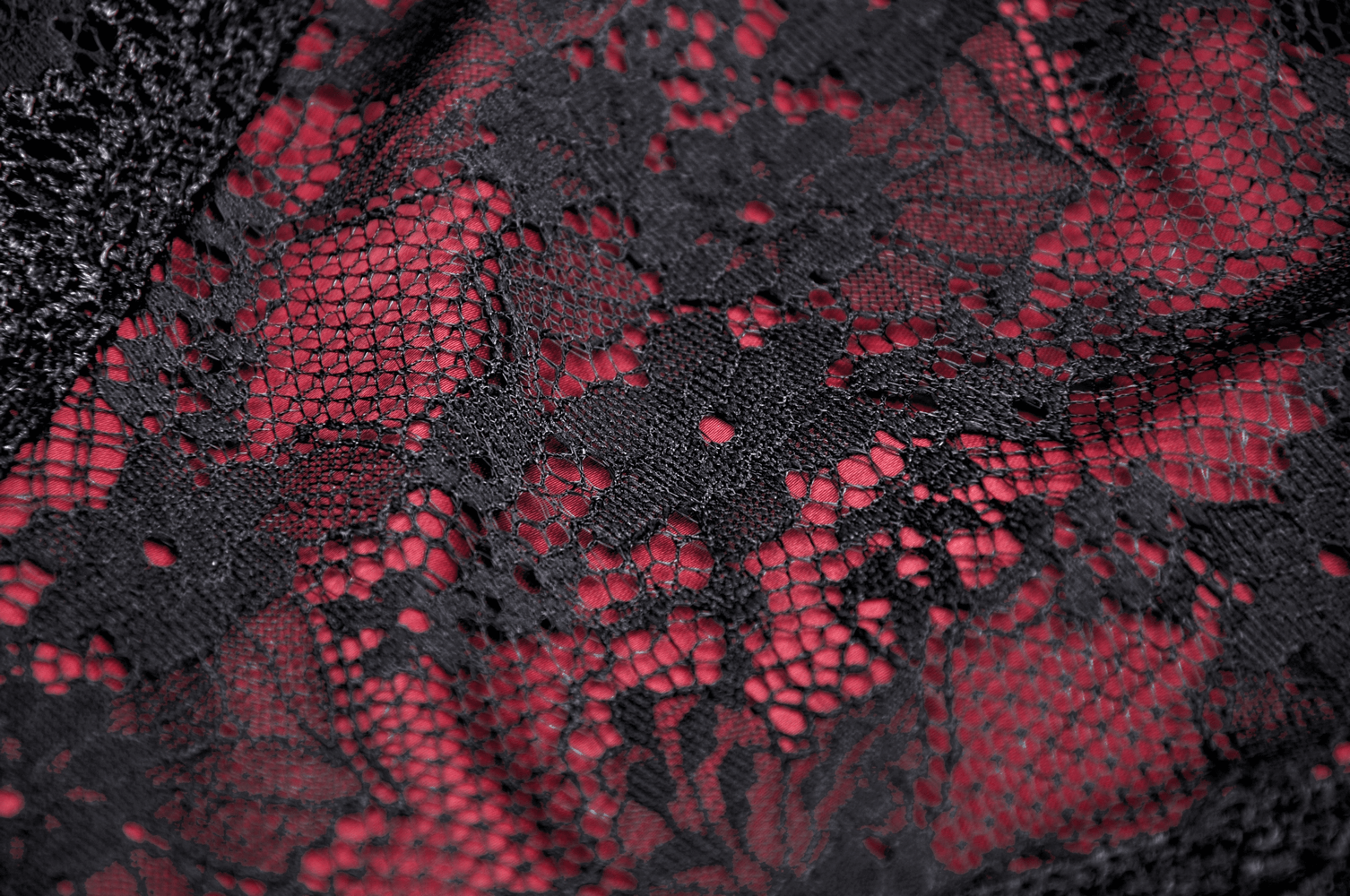 Close-up of intricate black lace with crimson accents, perfect for gothic and romantic fashion.