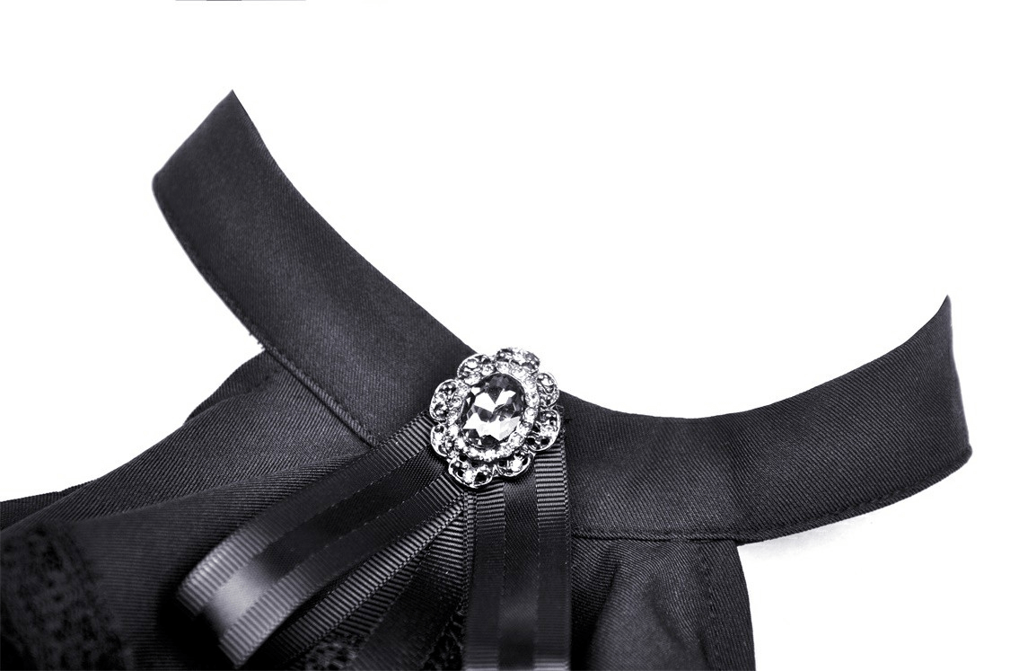 Close-up of the elegant collar and ribbon bow detail on a black gothic dress with a sparkling brooch accent.