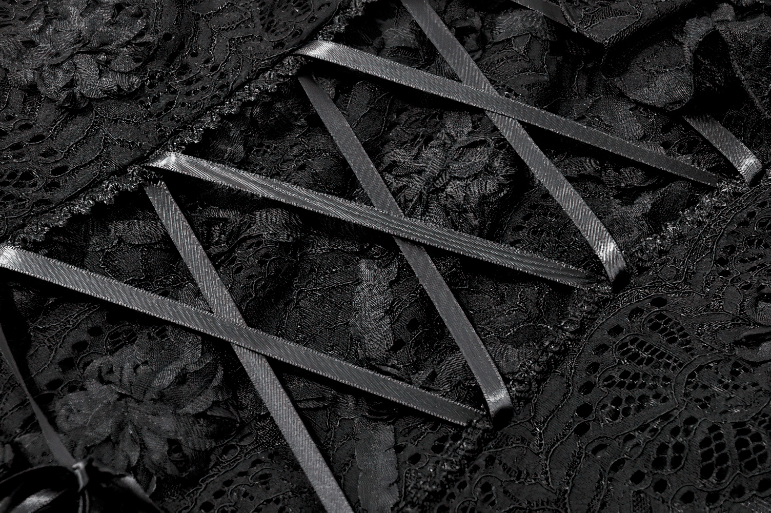 Close-up of the Dark Romantic Lace Mini Dress with Corset Waist and Cross featuring detailed floral lace and ribbon lacing.