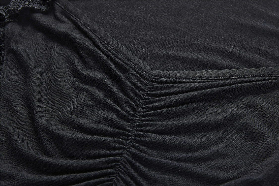 Close-up view of the ruched fabric detail on a dark black lace top, showcasing its unique texture and design.