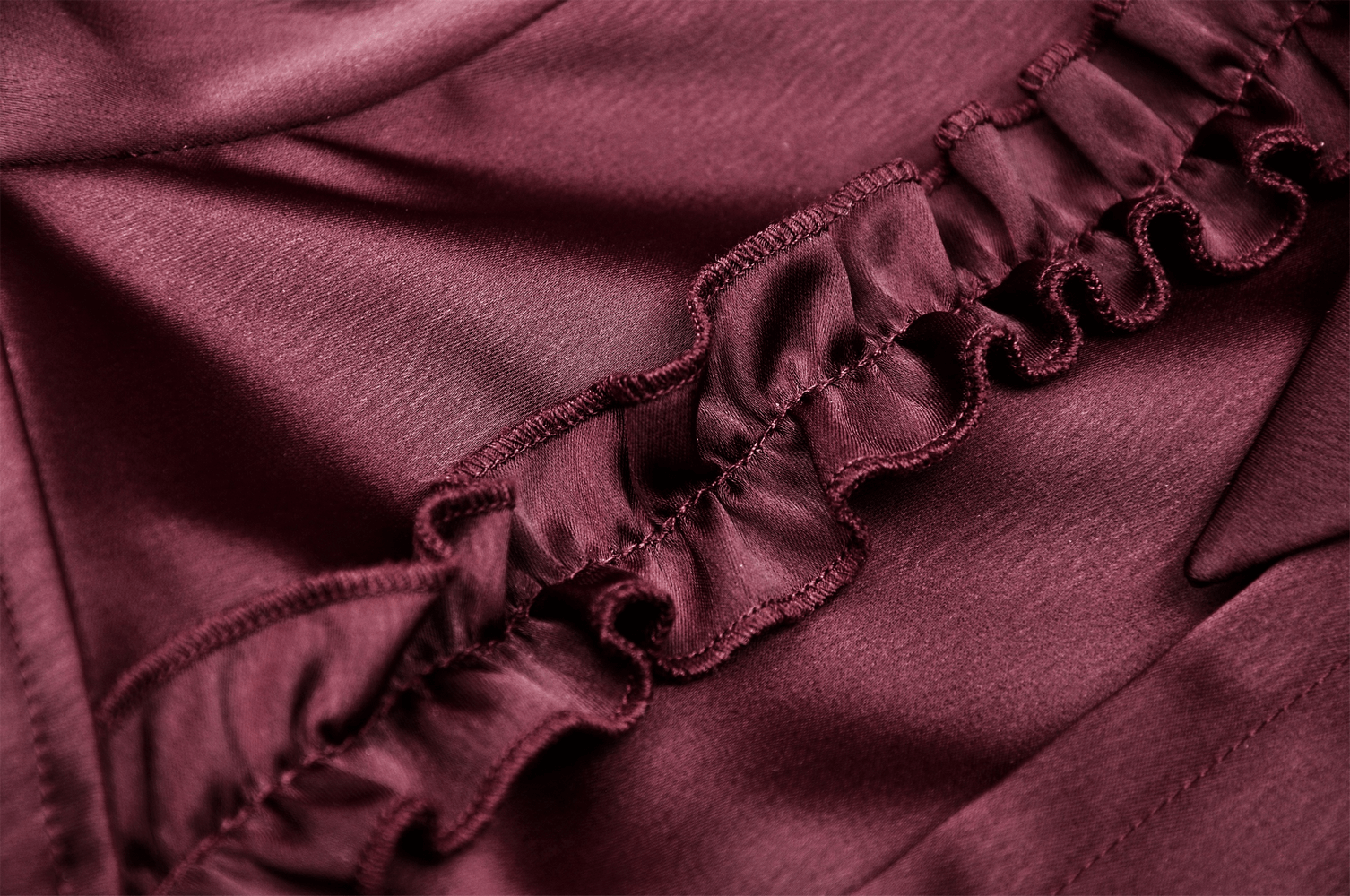 Close-up of luxurious wine red satin fabric with ruffled detail, showcasing vintage charm for a gothic blouse.