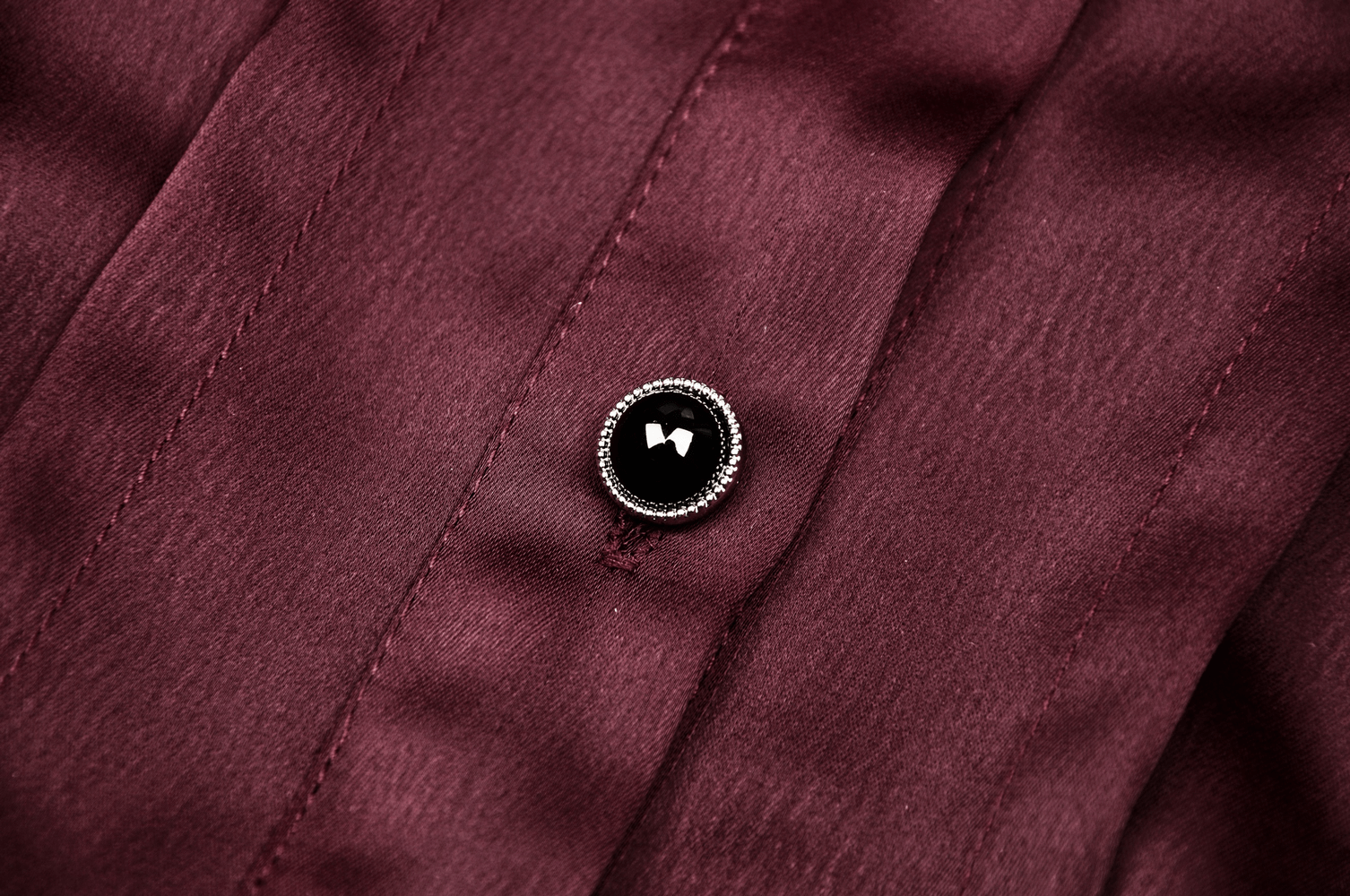 Close-up of a wine red blouse with a decorative black heart button, showcasing its gothic and romantic style.