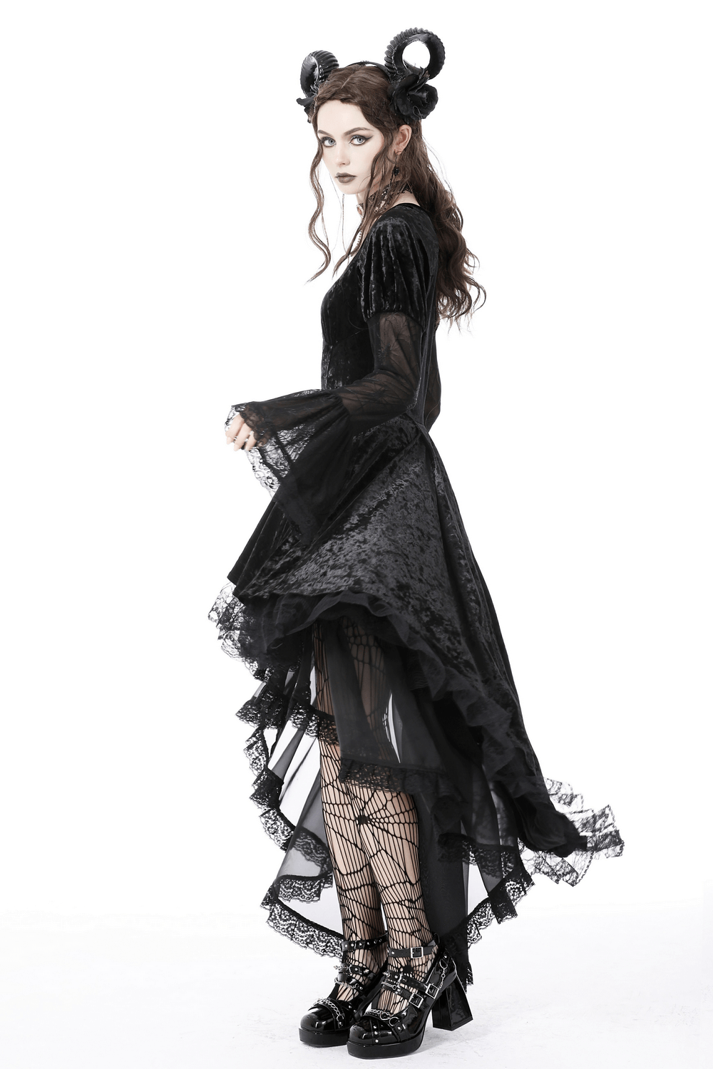 Gothic elegance in a high-low black velveteen dress with spiderweb lace, styled with dramatic hair and accessories.