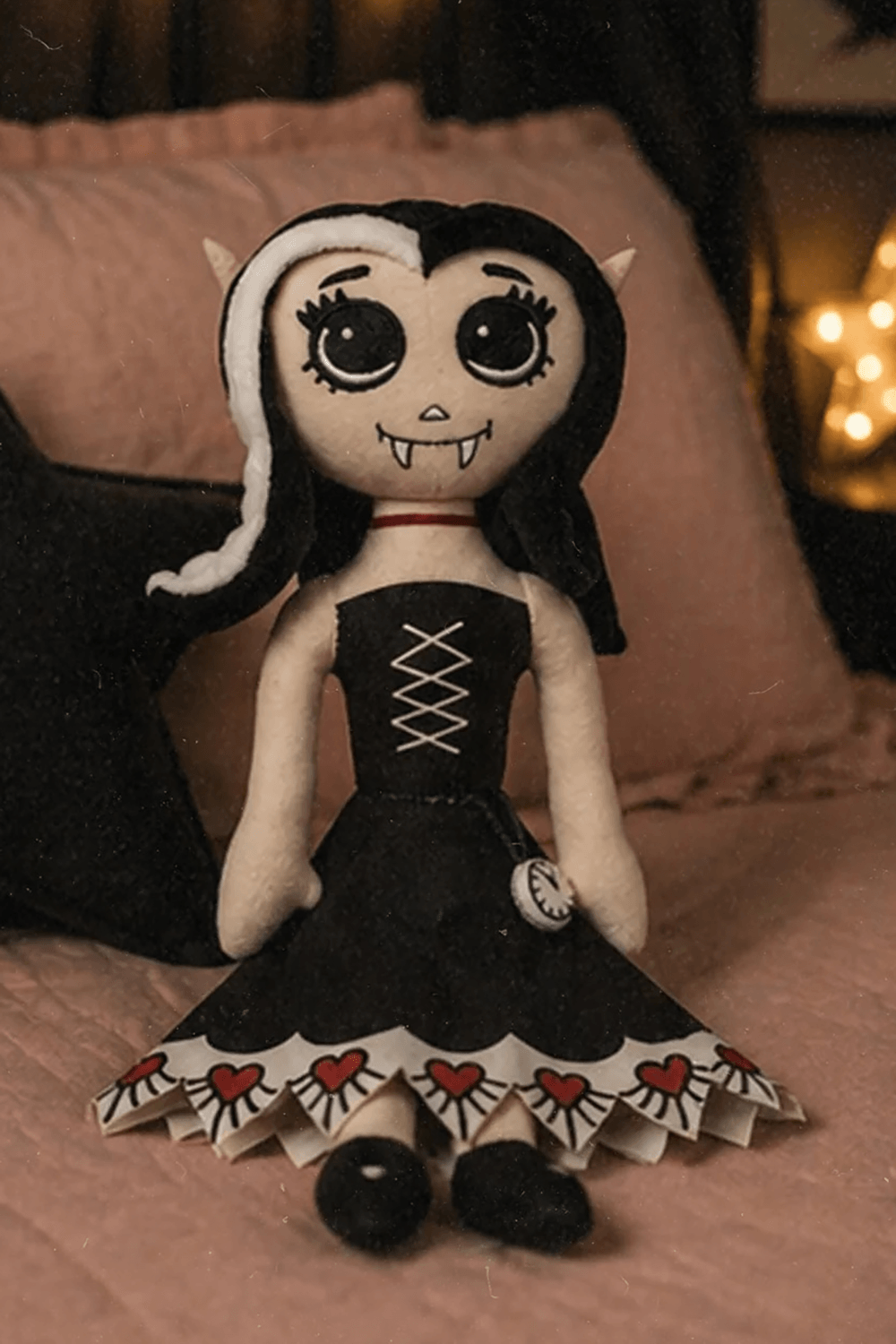 Dead Under The Bed Vampire Plush Doll Keepsake sitting on a bed with a star-shaped lamp behind her.
