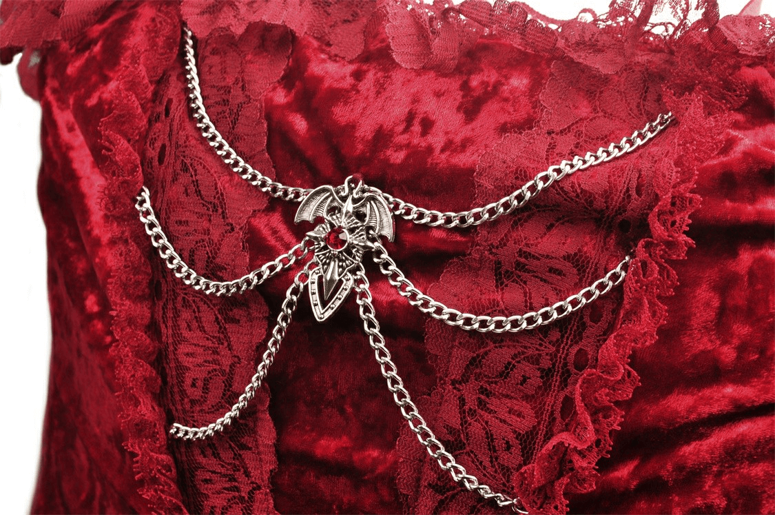 Close-up of gothic detail on deep red velvet maxi dress, featuring chain embellishments and bat pendant.