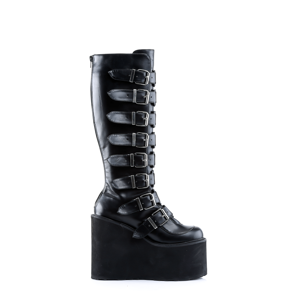 Demonia black knee-high platform boots with buckles, featuring a 5.5-inch wedge heel and sleek vegan leather design.