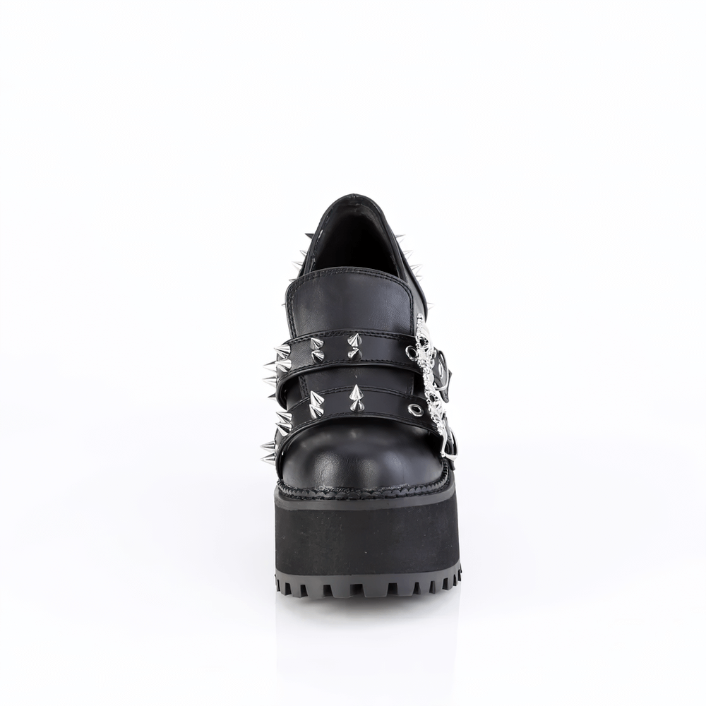 Black platform loafers with double skull buckles and cone spike details, featuring a bold block heel.