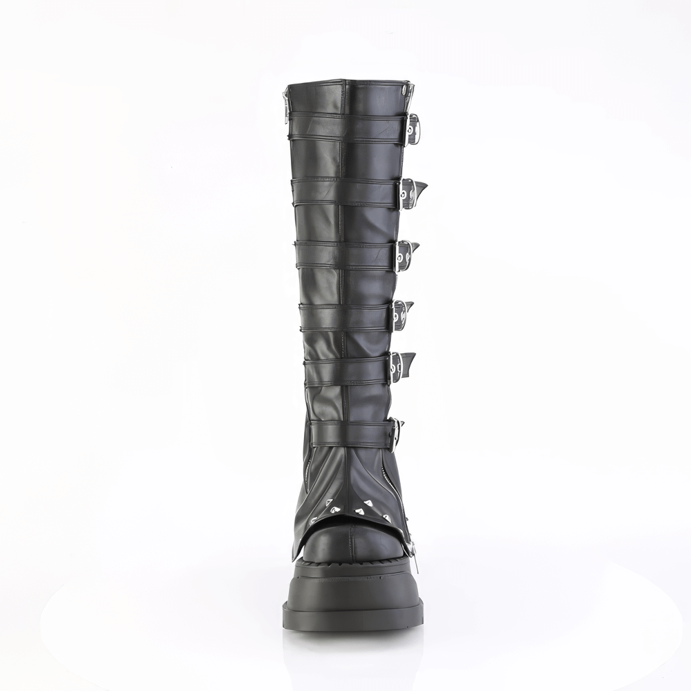 Daring black knee-high boots with ornamental buckle straps and cone studs, featuring a stylish platform and wedge heel.
