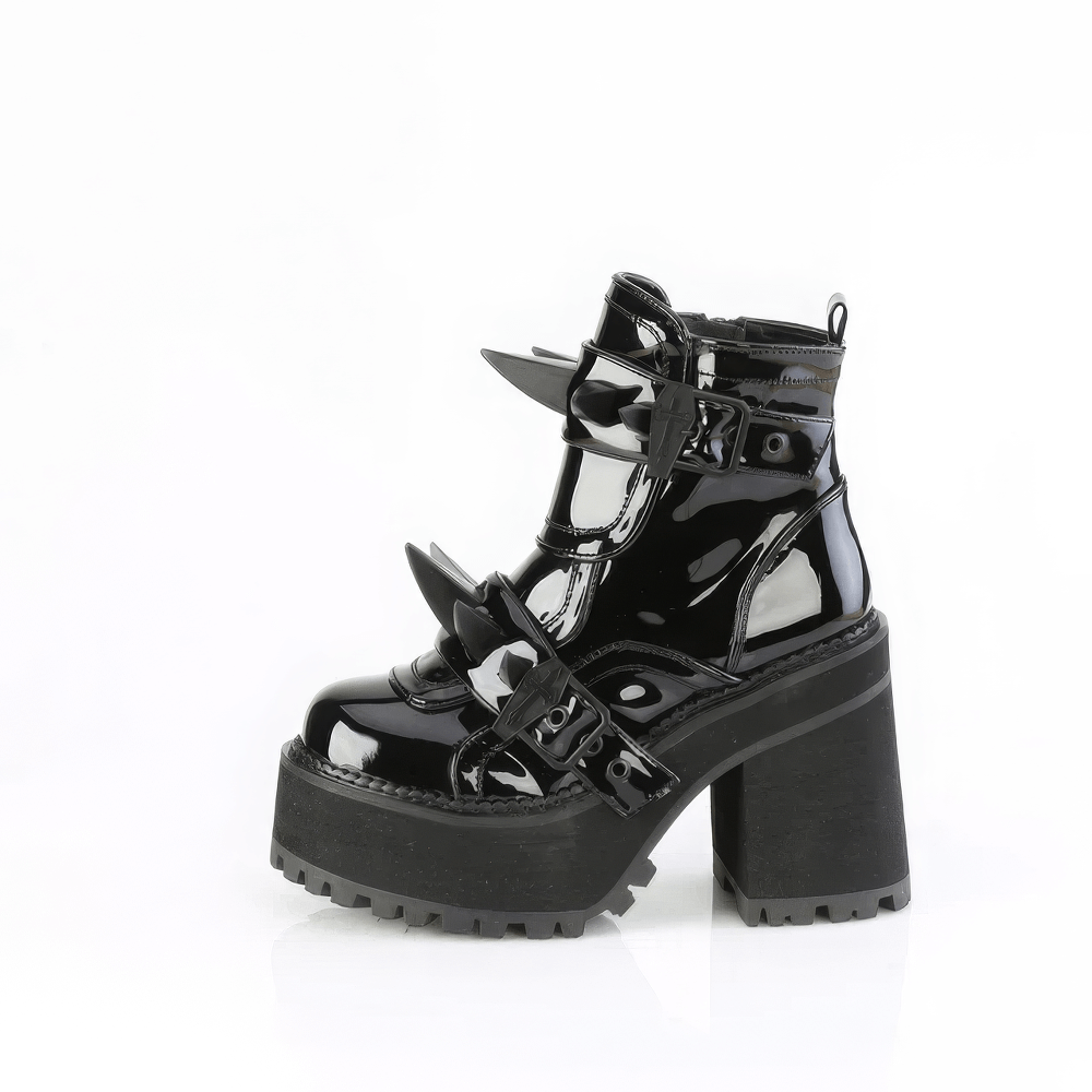 Demonia glossy black ankle boots with coffin buckle details and spike-studded shield, perfect for an edgy gothic look.