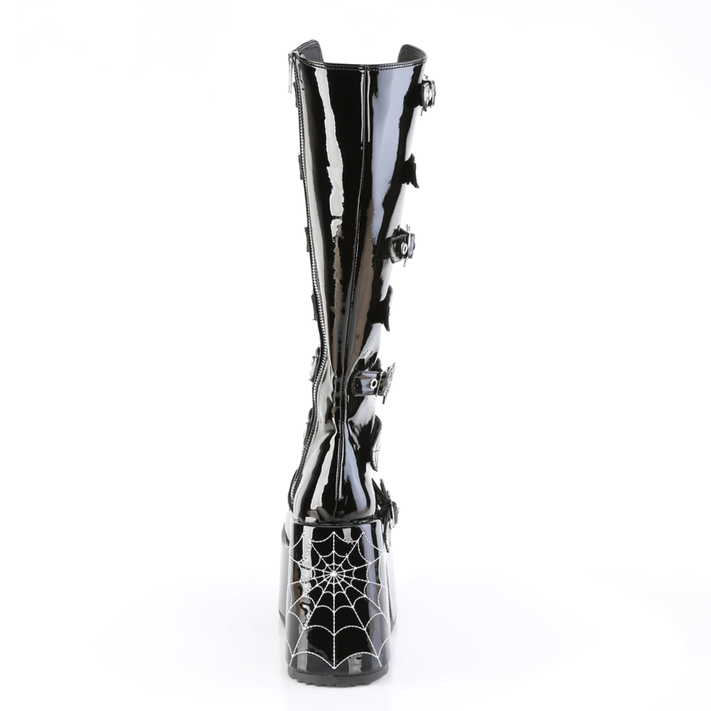 Demonia gothic knee-high boots with spider web buckles, shiny black finish, bold block heel, and stylish open front.