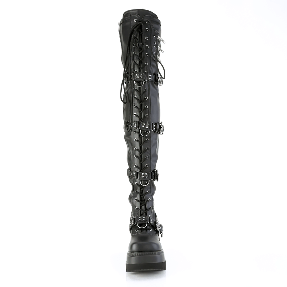 Gothic thigh-high boots with edgy skull buckle straps and lace-up details, made from black vegan leather.