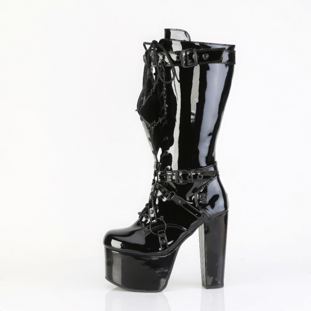 Knee-high Demonia platform boots with skull studs, harness straps, and barbed wire chain detail in shiny black patent leather.