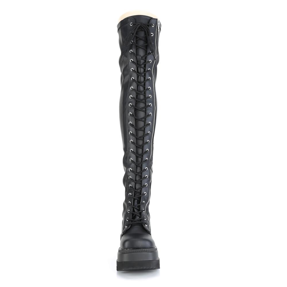 Demonia lace-up thigh-high platform boots in black stretch vegan leather with zipper detail.