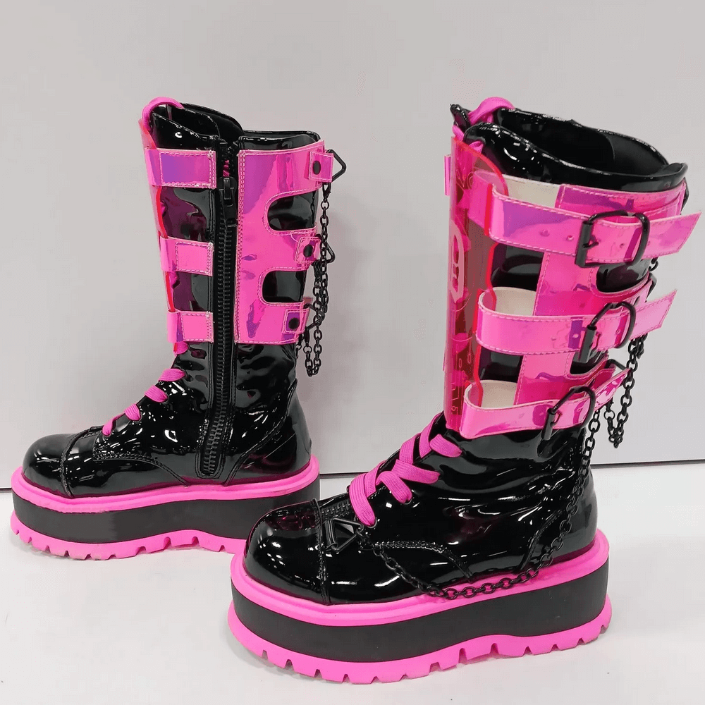 Demonia neon pink platform boots with clear straps, lace-up design, chain details, and mid-calf height for edgy goth style.