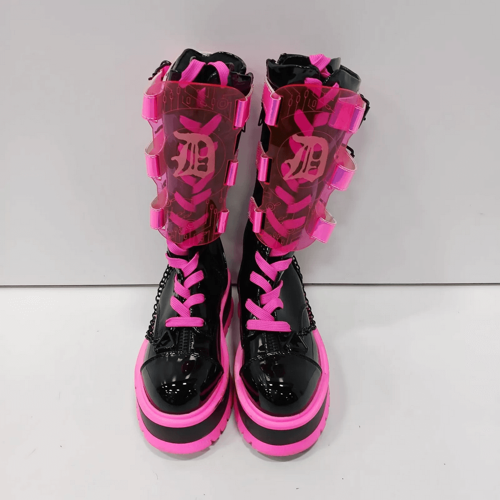 Demonia neon pink platform boots with clear straps, featuring lace-up design and edgy chain details. Perfect for goth fashion!