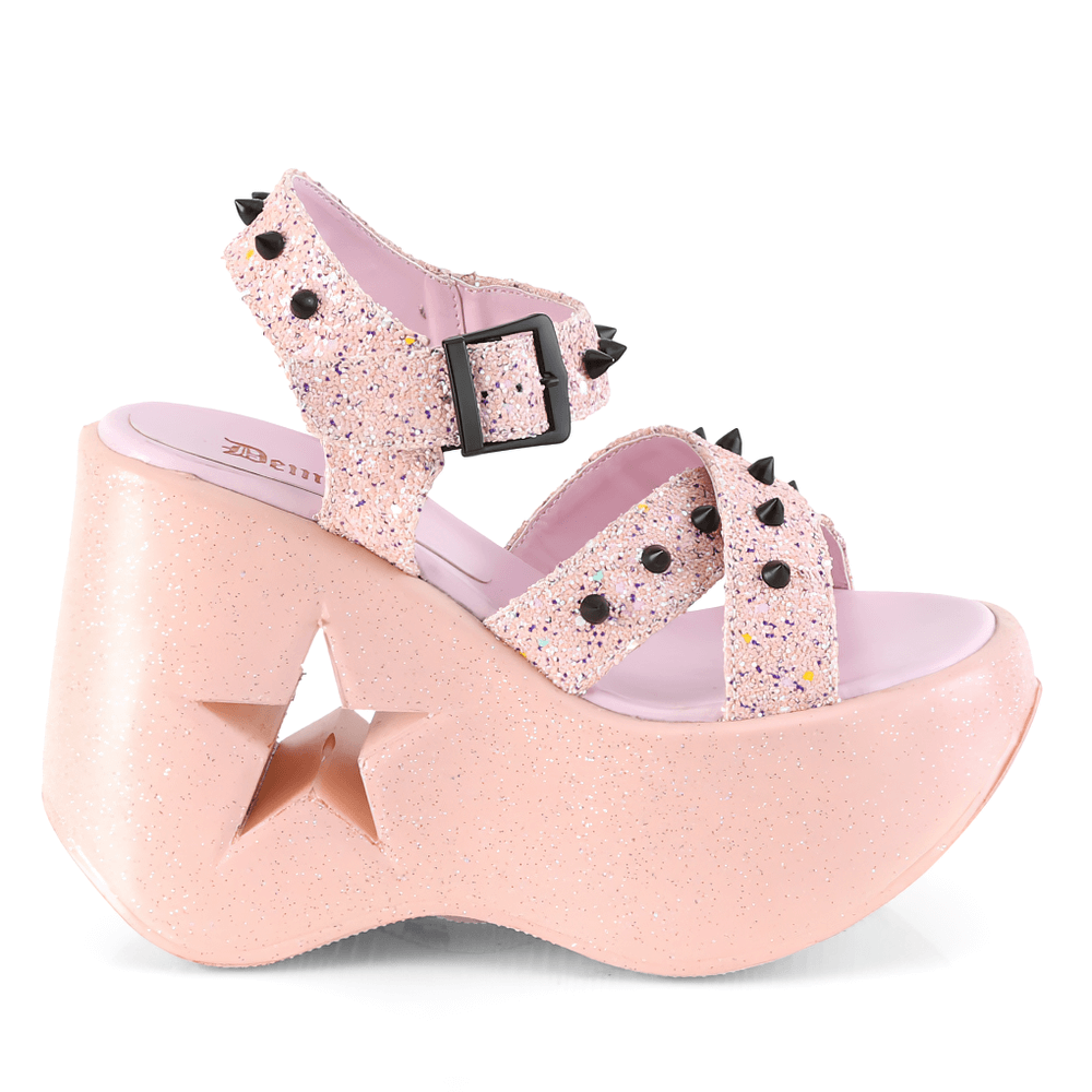 Demonia pink glitter star wedge sandals with spike accents, featuring criss-cross ankle straps and bold star cutout design.