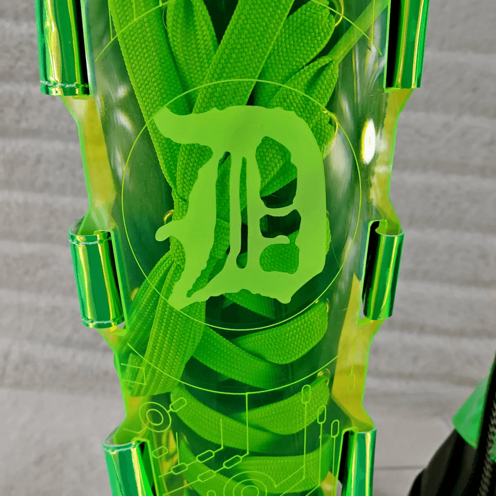 Close-up of neon green laces within a transparent boot section featuring a unique design and logo.