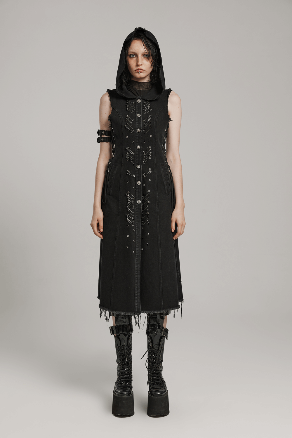 Punk-inspired denim hooded cape with safety pins, raw edges, and adjustable drawstrings for a customizable fit.