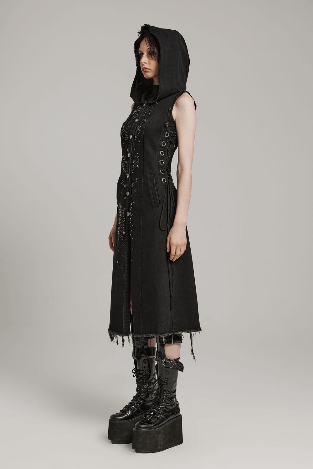 Edgy denim hooded cape with punk safety pins and raw edges, styled with bold platform boots.