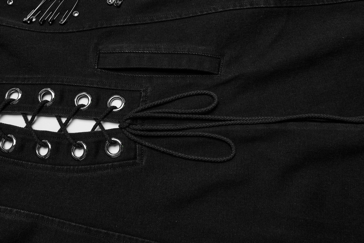 Close-up of punk-inspired denim cape detailing with laces and safety pins for an edgy look.