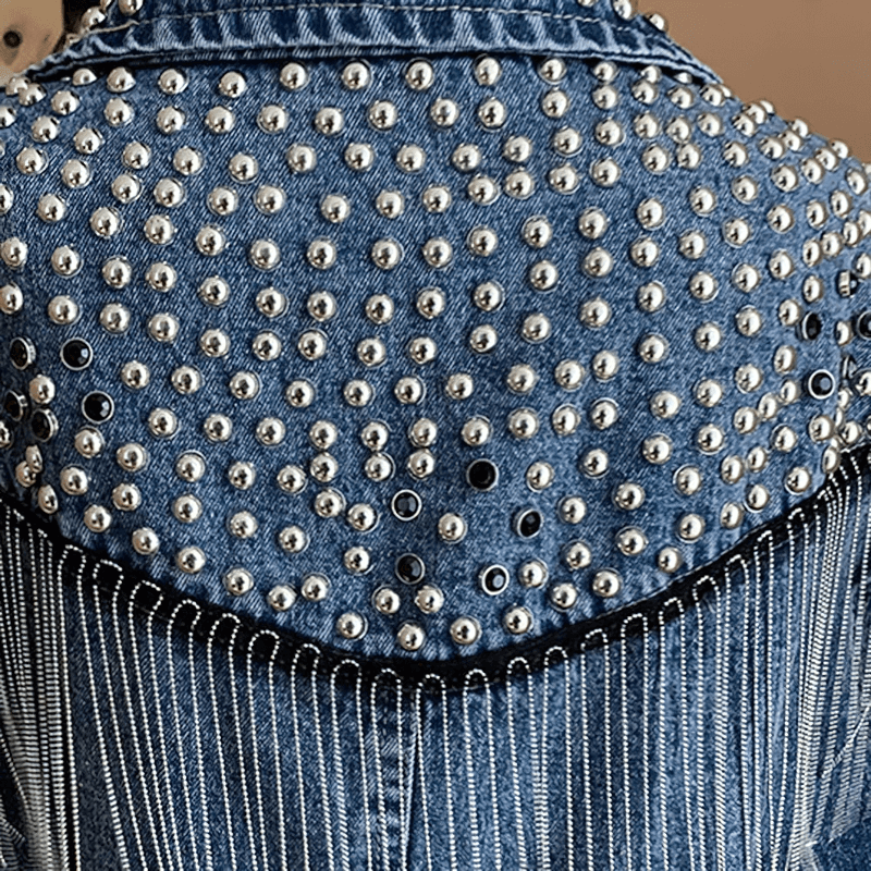 Back view of denim women's jacket with silver rivets, tassels, and stylish fringe for casual streetwear.