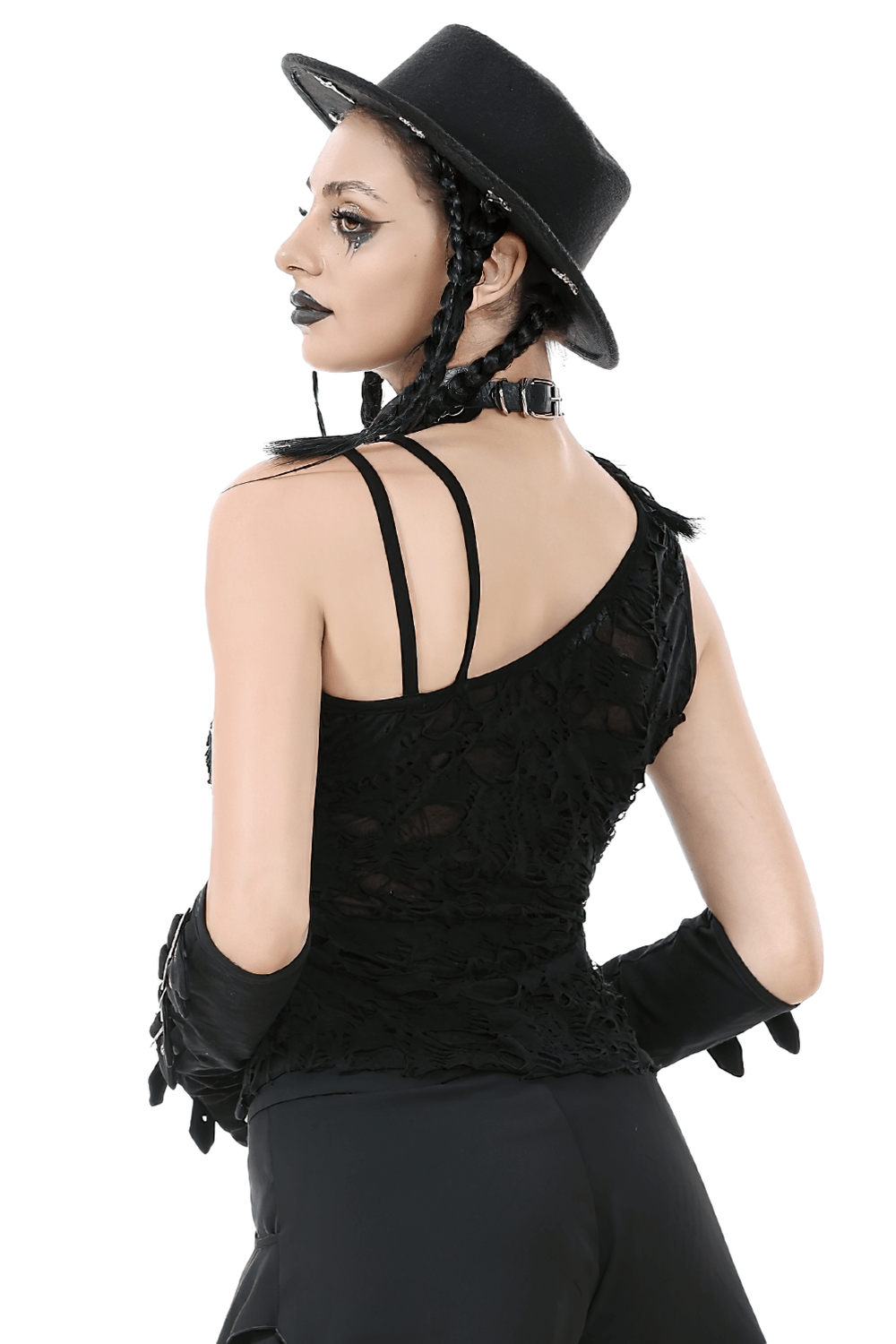 Stylish model in a distressed asymmetrical gothic top with grommet straps and a hat, showcasing punk fashion vibes.