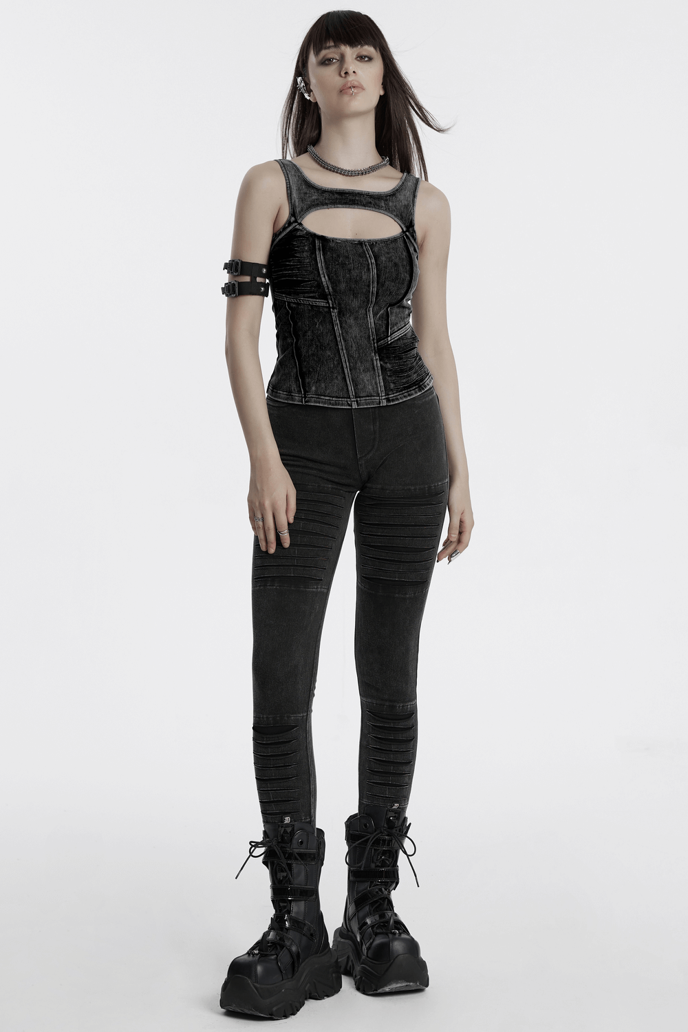 Model wearing distressed black denim tank top with cutout detail and punk-inspired bottoms, showcasing edgy fashion style.