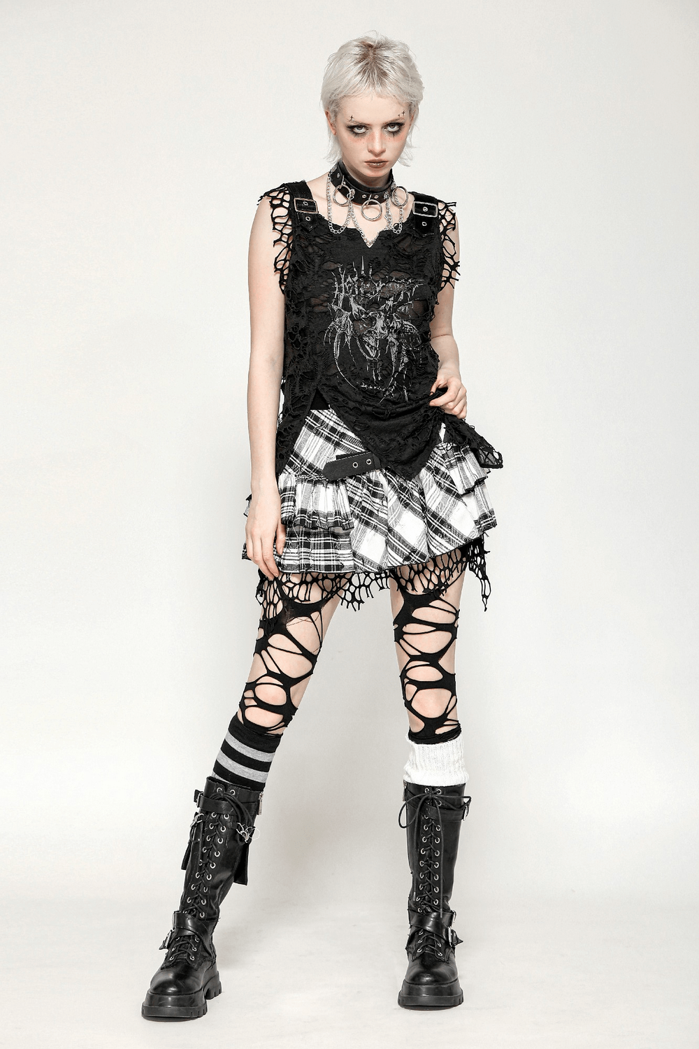 Gothic punk fashion featuring a black sleeveless tank top with skull print and grunge-inspired skirt and leggings.