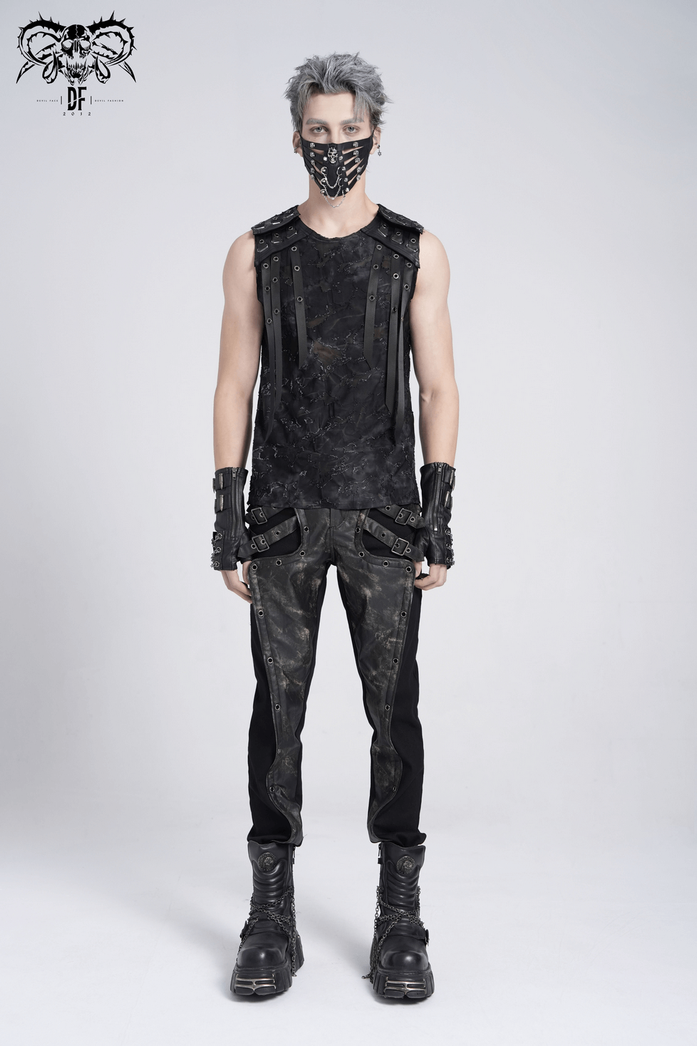 Stylish man in distressed black sleeveless top with eyelet straps, wearing a mask and edgy accessories.